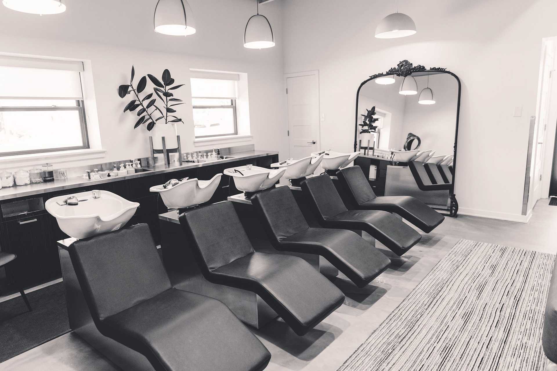 Monochrome image of a modern salon interior with hair-washing stations.