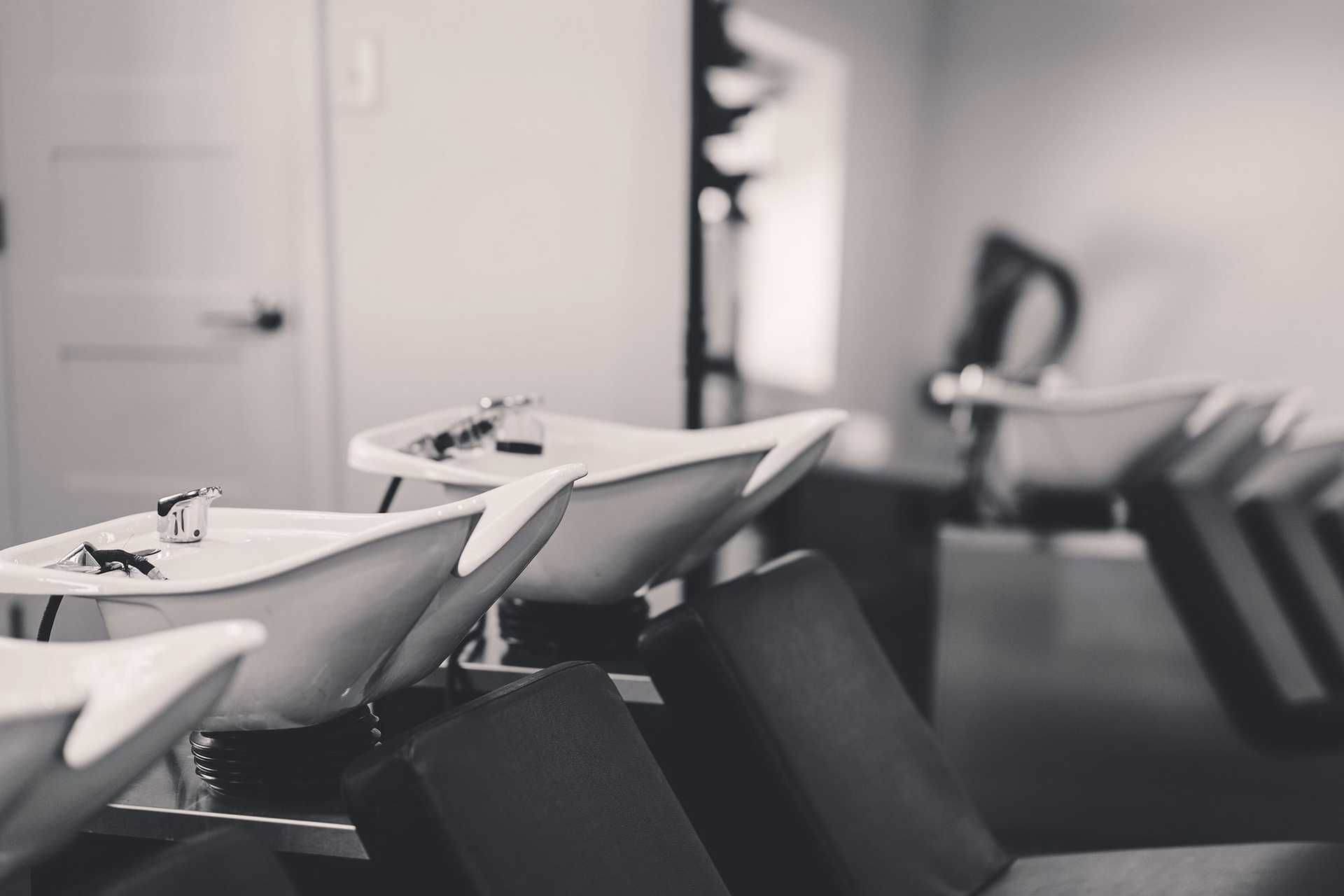 Hair salon wash stations with reclining chairs in monochrome.